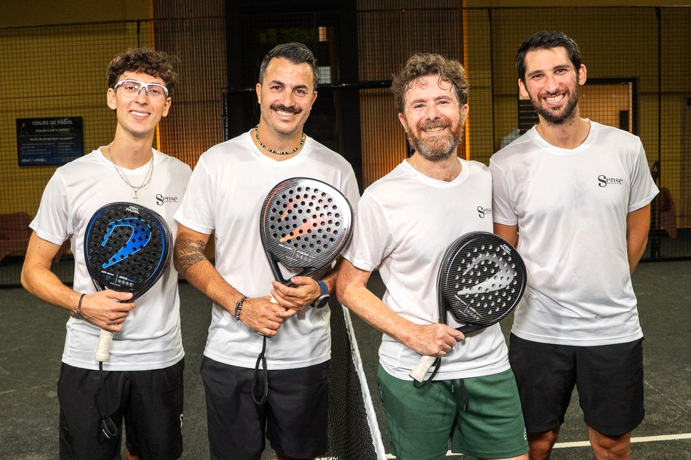 Quatre membres souriants avec leurs raquettes après une soirée padel Wolk Experiences