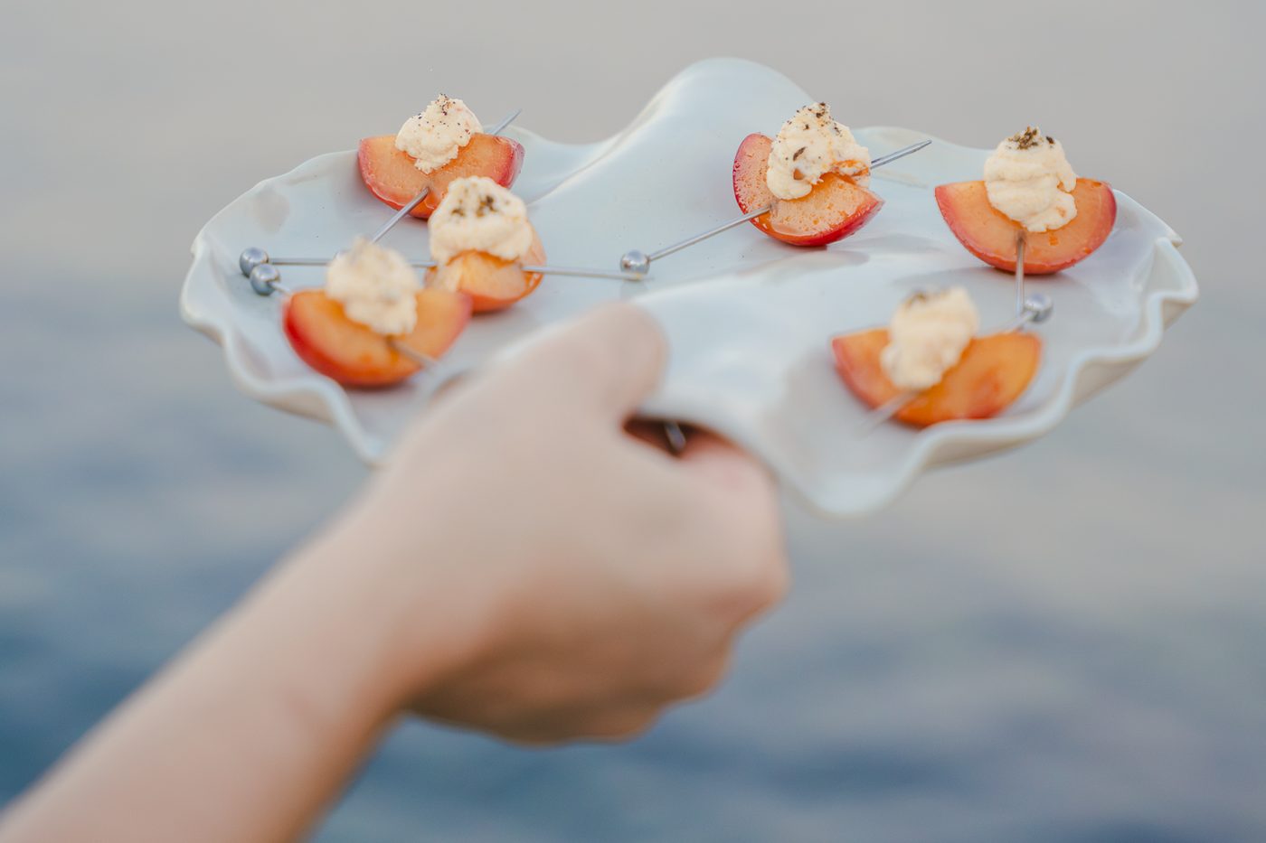 Amuse-bouches à la prune et crème servis sur un plat en céramique face à la mer lors d’une soirée Wolk Table à Marseille